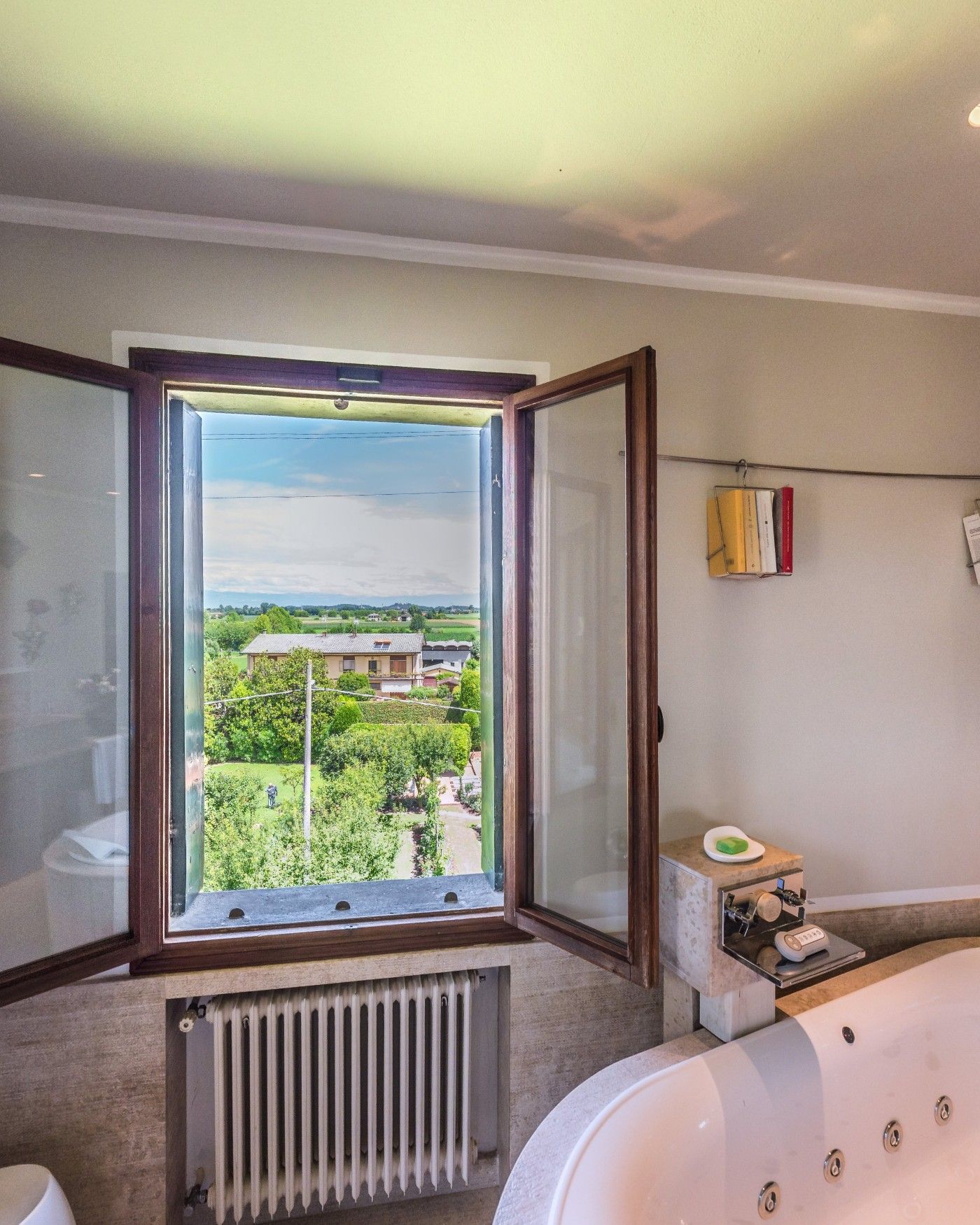 A bathroom window open onto the countryside, a jacuzzi below