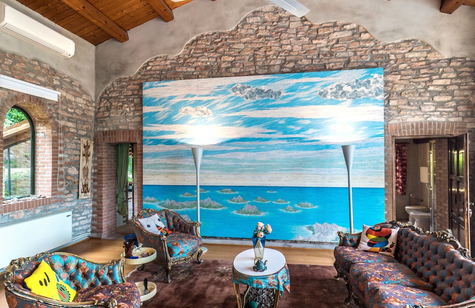 The Loft: stone walls, a timber roof and a large sea painting above patterned sofas
