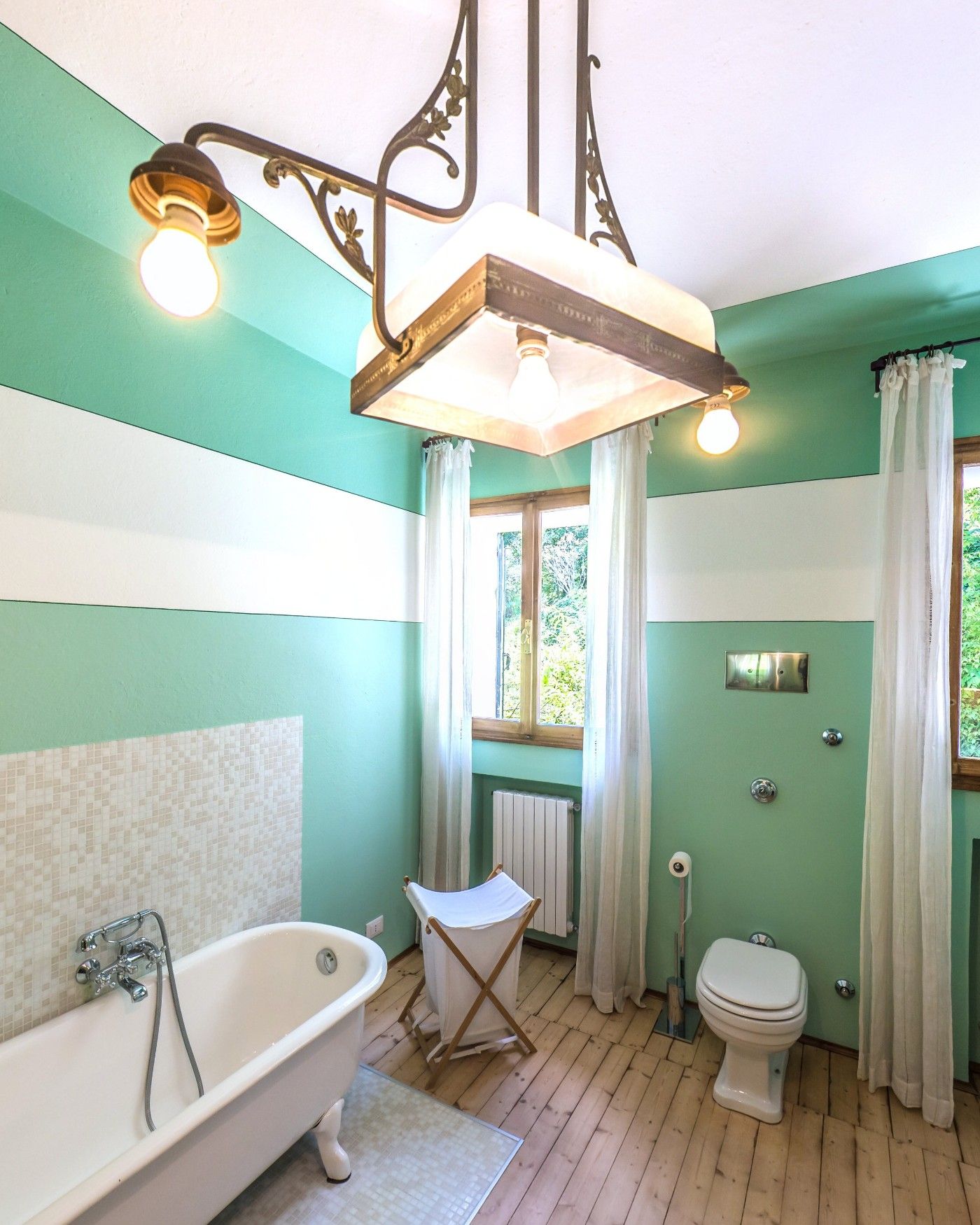 A mint green bathroom with a claw-foot tub