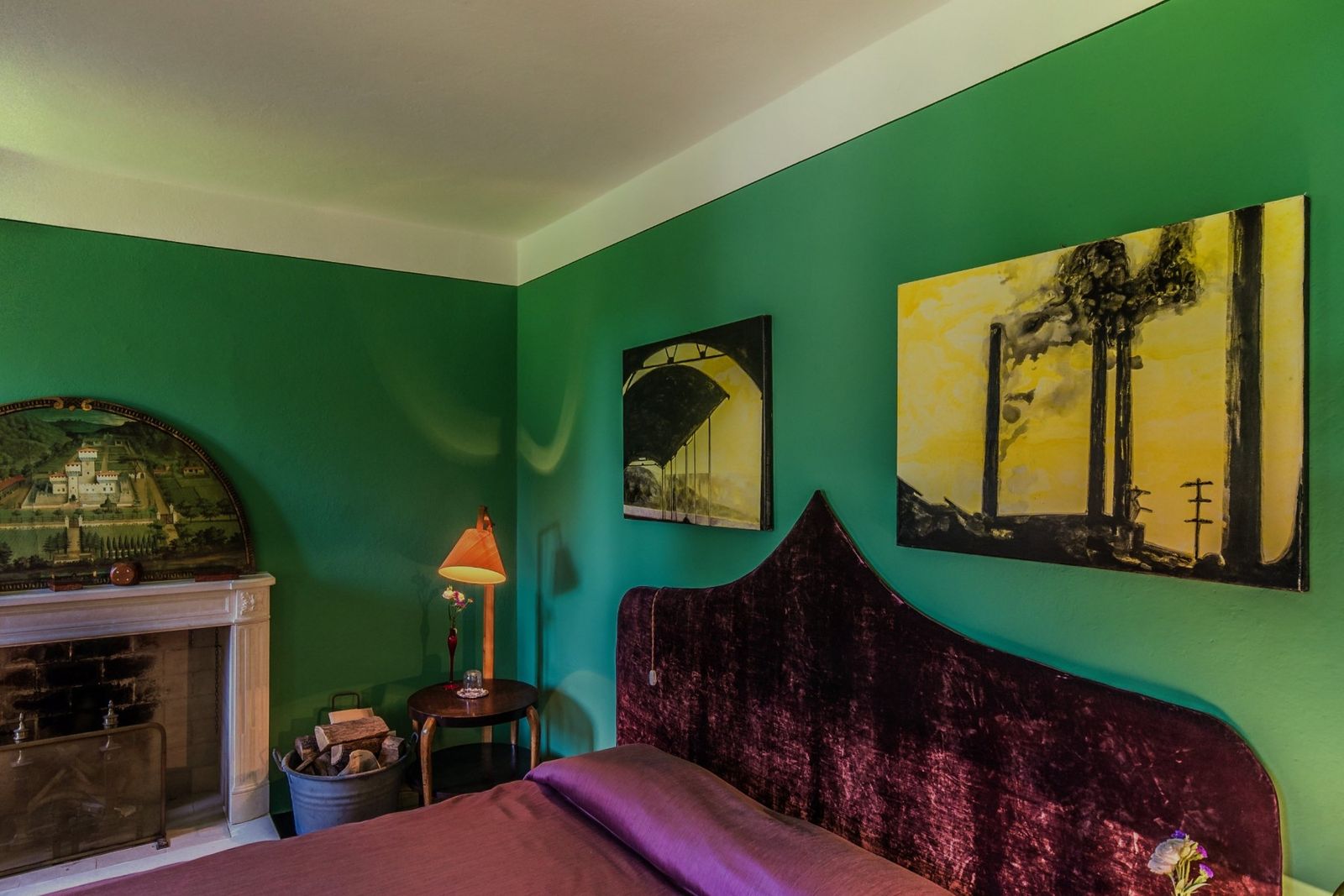 A bedroom with deep green walls and a purple bed