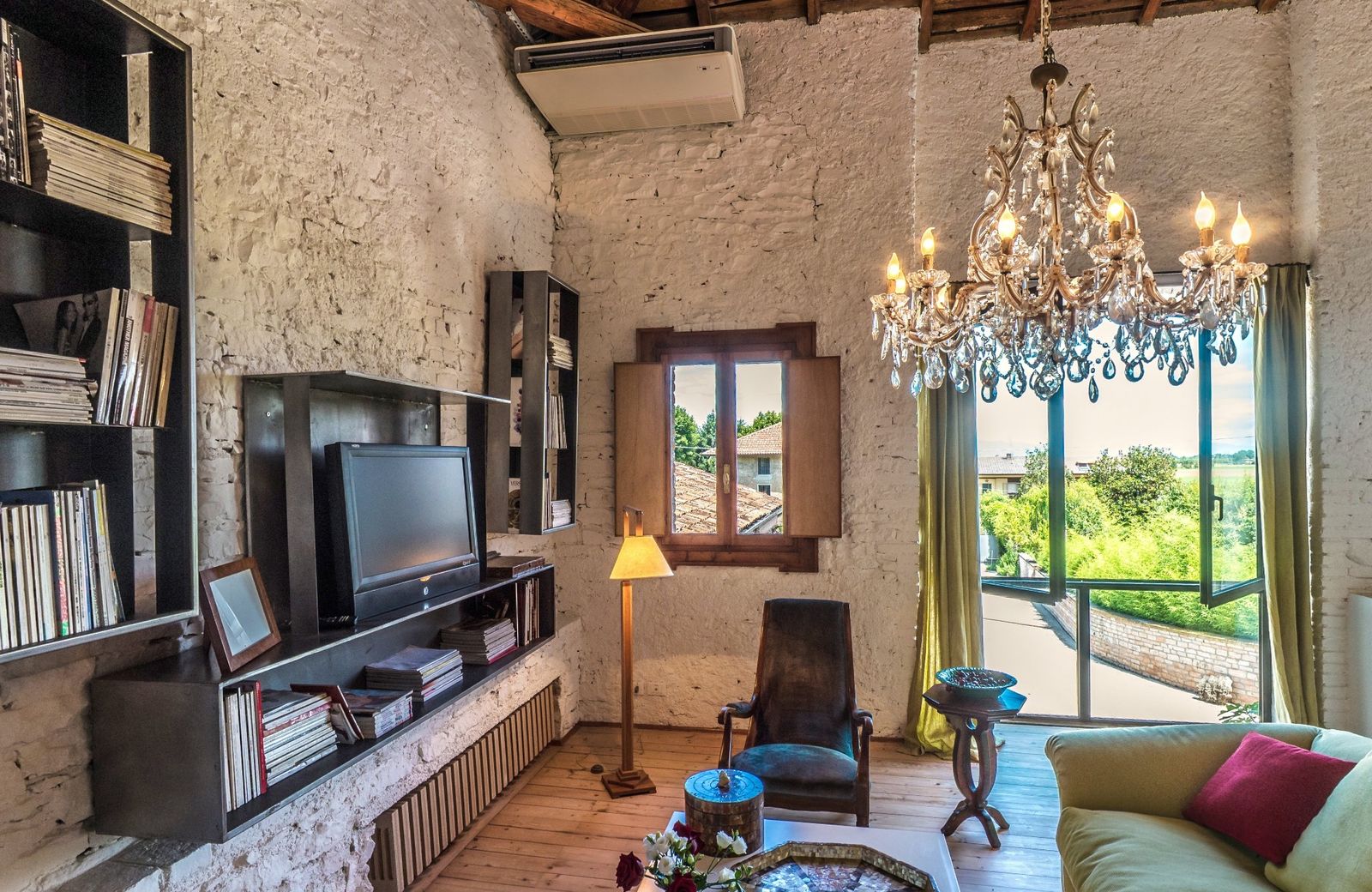 Seraphim living room: white stone walls, a crystal chandelier and a green sofa