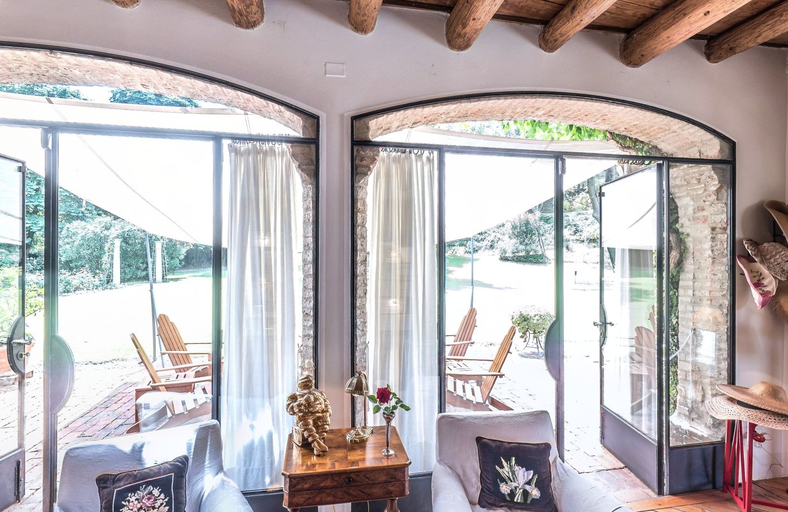 The living room with arched glass doors onto the veranda, beams and armchairs